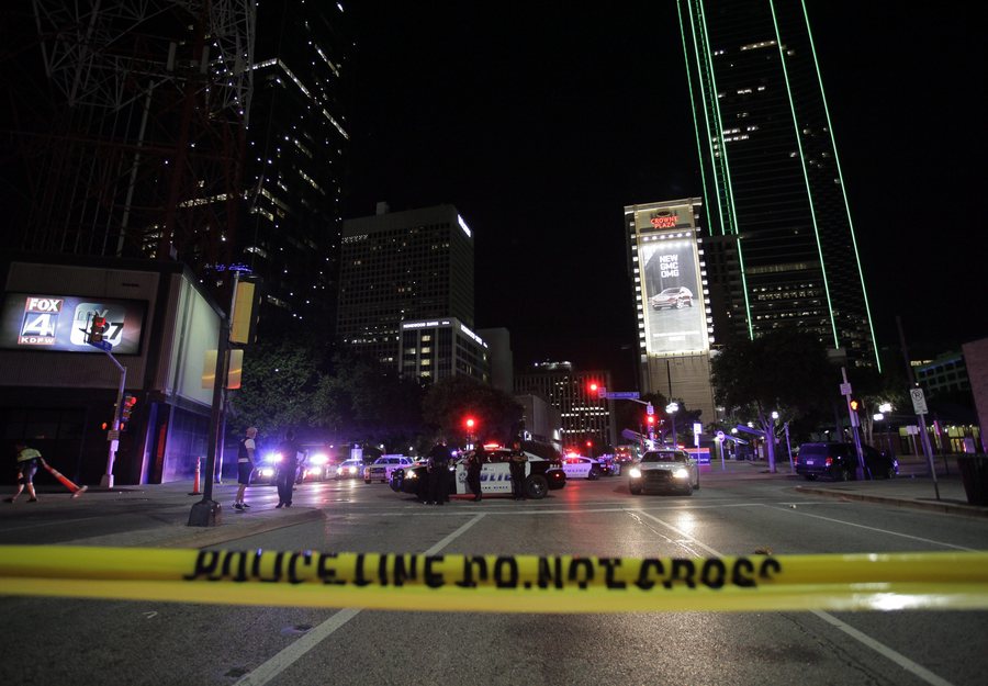 epaselect epa05414446 Dallas police officers face protesters on the corner of on the corner of Ross Avenue and Griffin Street after eleven police officers were shot during a peaceful protest in Dallas, Texas, USA, 08 July 2016. Police report that five officers have died as a result of their injuries as it appeared that two snipers shot the police from elevated positions during a protest rally in Dallas on 07 July.  EPA/RALPH LAUER