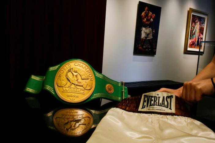 A woman arranges the short and the iconic 'Rumble in the Jungle' belt of late boxing champion Muhammad Ali at Heritage Auctions house in Manhattan, New York, U.S., August 19, 2016. REUTERS/Eduardo Munoz