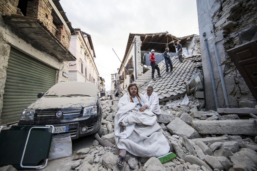 epa05508230 Residents look on as they stand on the rubble of collapsed buildings in Amatrice, central Italy, 24 August 2016, following a 6.2 magnitude earthquake, according to the United States Geological Survey (USGS), that struck at around 3:30 am local time (1:30 am GMT). The quake was felt across a broad section of central Italy, including the capital Rome where people in homes in the historic center felt a long swaying followed by aftershocks. According to reports at least 21 people died in the quake, 11 in Lazio and 10 in Marche regions.  EPA/MASSIMO PERCOSSI