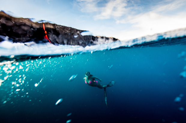 PIC BY PERRIN JAMES / CATERS NEWS - (PICTURED: Alison Teal paddles out to Kilauea volcano in Hawaii as it eruopts into the ocean) - Professional adventurer Alison Teal has become the first woman to paddle out into lava during a volcanic eruption into the sea. Amazing shots of the extreme surf session shows the daredevil riding her pink surfboard up to the base of Kilauea Volcano. Photographer Perrin James snapped the brave explorer within feet of the lava as it flows into the ocean. Its the first the volcano in the Big Island of Hawaii has erupted since 2011. SEE CATERS COPY