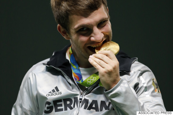 Henri Junghaenel of Germany bites his gold medal during the award ceremony for men's 50-meter rifle prone finals, at the Olympic Shooting Center at the 2016 Summer Olympics in Rio de Janeiro, Brazil, Friday, Aug. 12, 2016. (AP Photo/Hassan Ammar)