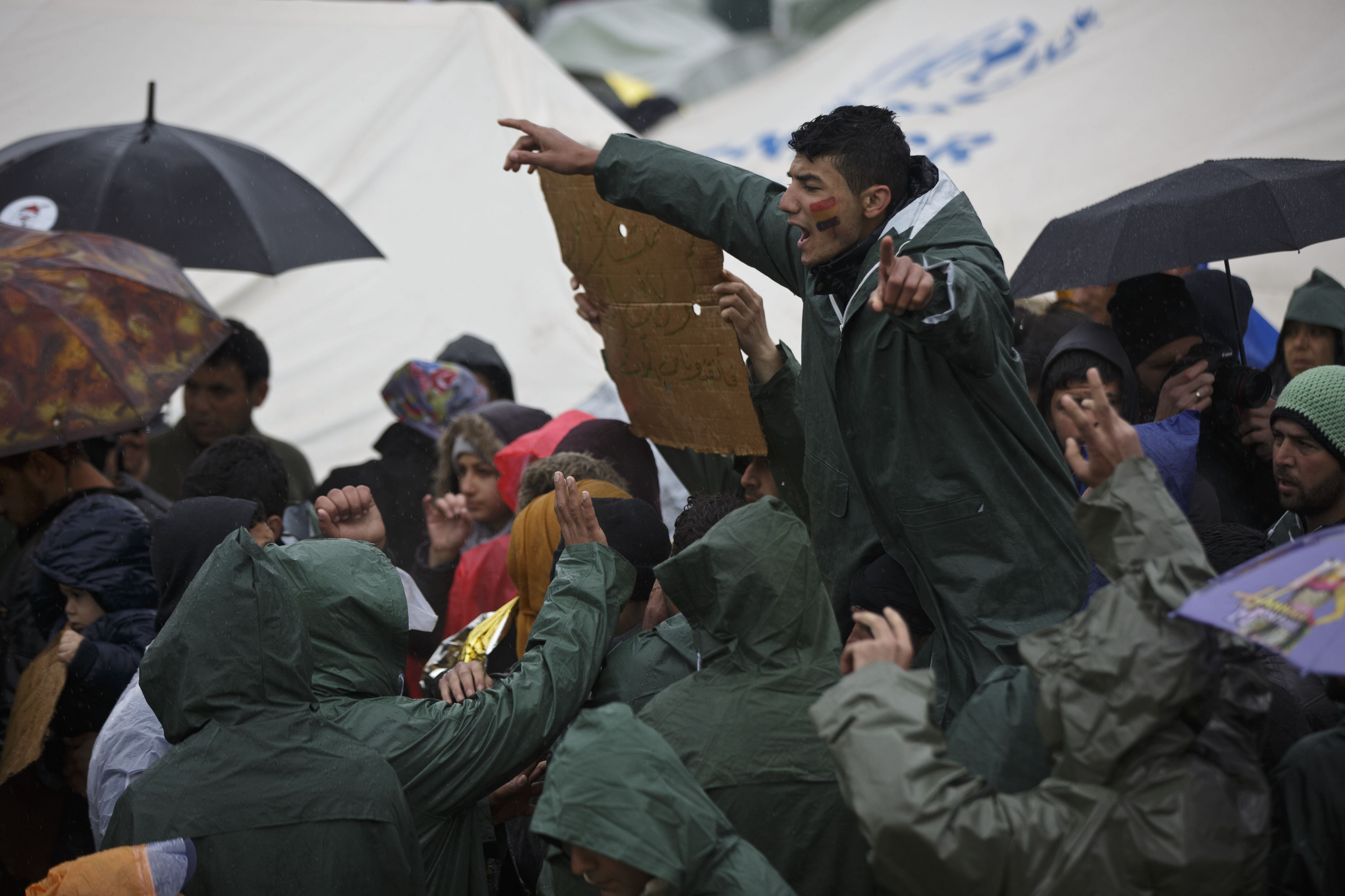 A migrant shouts in protest about the poor conditions and demanding the opening of the Macedonia border at a makeshift camp at the northern Greek border station of Idomeni, Sunday, March 13, 2016. Bad weather returned after a brief pause and conditions in the refugee camp on the Greek-Macedonian where about 14,000 people are stranded have further deteriorated, many of its residents struggling to cope with the many challenges posed by the heavy rain. (AP Photo/Visar Kryeziu)