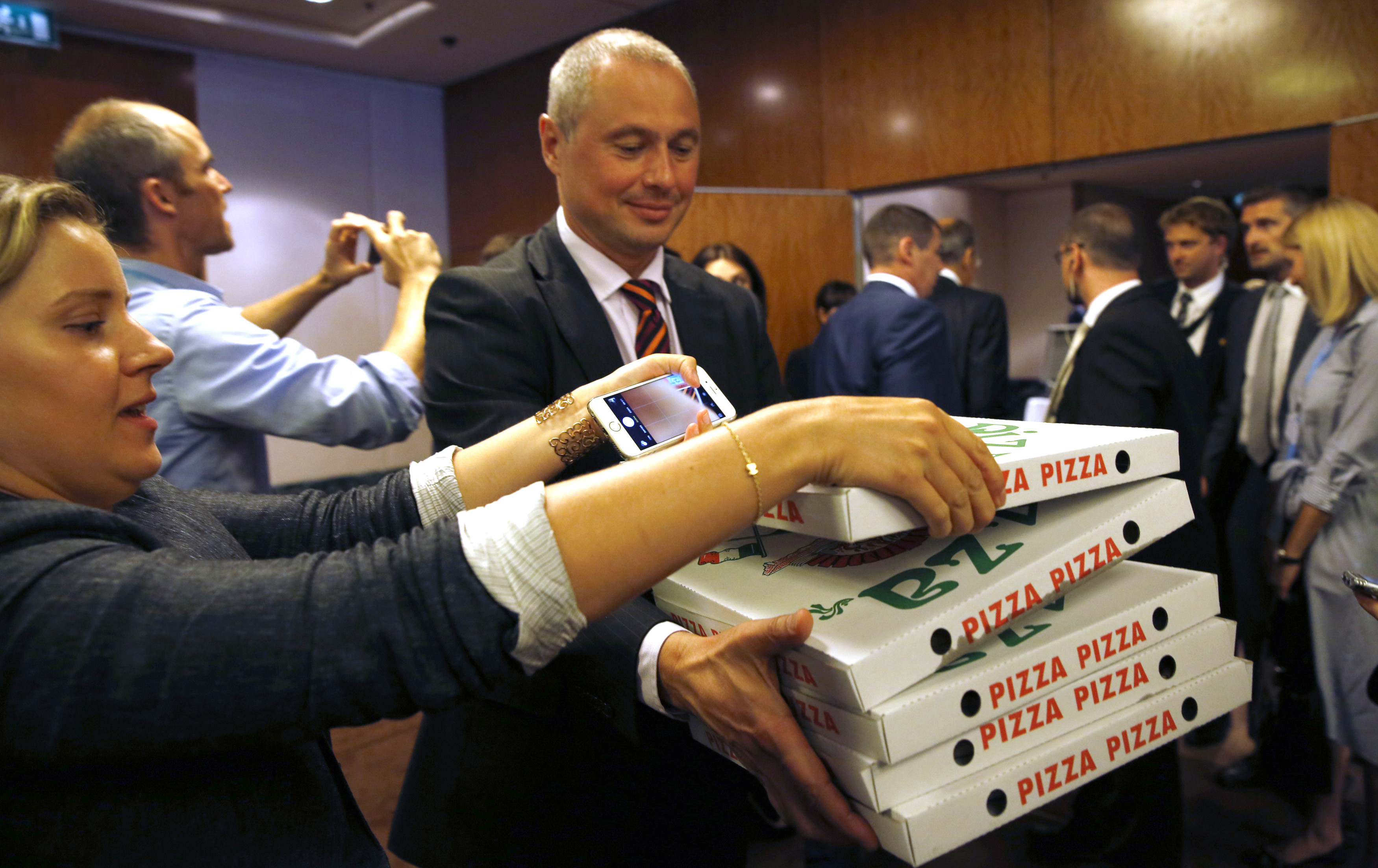 Alexander Zorin from a Russian delegation carries pizzas to reporters awaiting a late night press conference by U.S. Secretary of State John Kerry and Russian Foreign Minister Sergei Lavrov in Geneva, Switzerland, Friday, Sept. 9, 2016. (Kevin Lamarque/Pool Photo via AP)