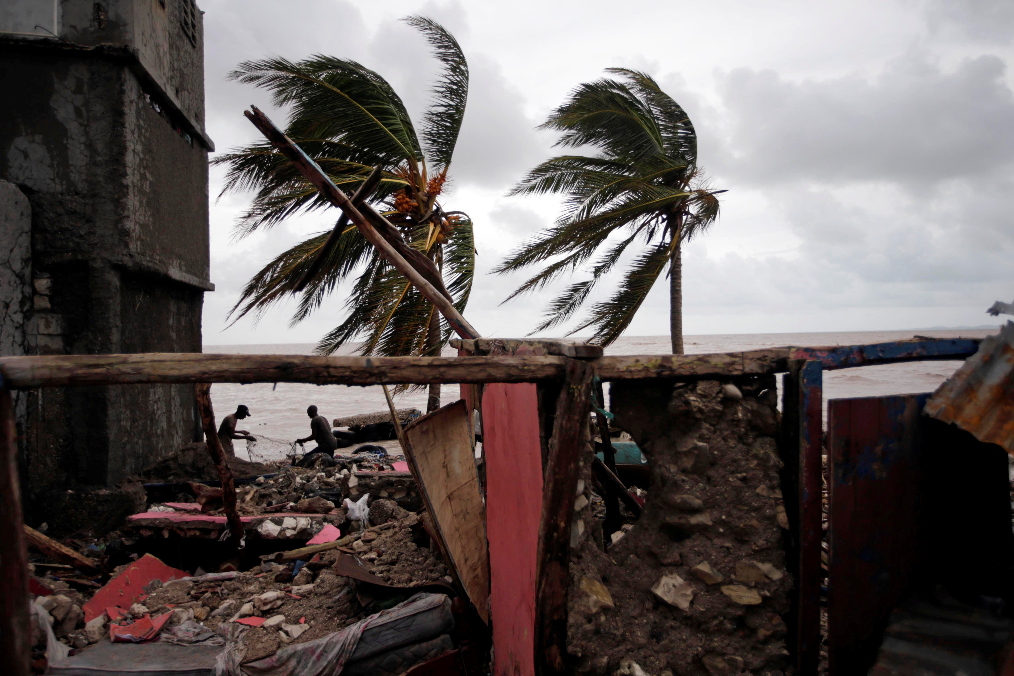 Two fishermen fix a net near the remains of a house destroyed by Hurricane Matthew in Les Cayes, Haiti, October 5, 2016. REUTERS/Andres Martinez Casares