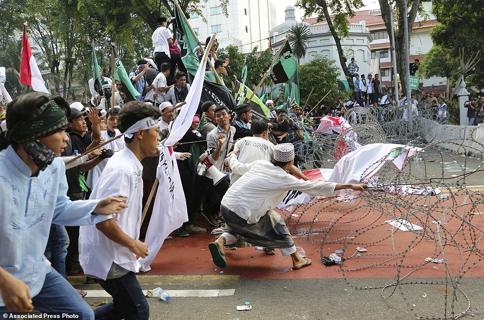 Muslim protesters pull razor wire blocking a road that leads to the presidential palace during a rally against Jakarta Governor Basuki Tjahaja Purnama in Jakarta, Indonesia, Friday, Nov. 4, 2016. Tens of thousands of hard-line Muslims marched Friday on the center of the Indonesian capital to demand the arrest of the minority-Christian governor for alleged blasphemy. (AP Photo/Tatan Syuflana)