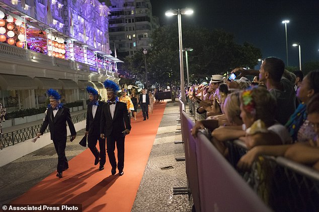 Guests walk on the red carpet as they arrive to a traditional Carnival ball at the Copacabana Palace hotel in Rio de Janeiro, Brazil, Saturday, Feb. 25, 2017. In stark contrast to the hundreds of hard-charging street parties across Rio that are open to anyone, the "Baile do Copa" bills itself as a fairytale event where the country's elite can see and be seen in a hotel known for both opulence and a lengthy tradition of welcoming world leaders and stars. (AP Photo/Leo Correa)