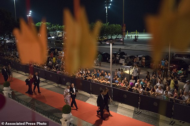 Guests walk on the red carpet as they arrive to a traditional Carnival ball at the Copacabana Palace hotel in Rio de Janeiro, Brazil, Saturday, Feb. 25, 2017. In stark contrast to the hundreds of hard-charging street parties across Rio that are open to anyone, the "Baile do Copa" bills itself as a fairytale event where the country's elite can see and be seen in a hotel known for both opulence and a lengthy tradition of welcoming world leaders and stars. (AP Photo/Leo Correa)