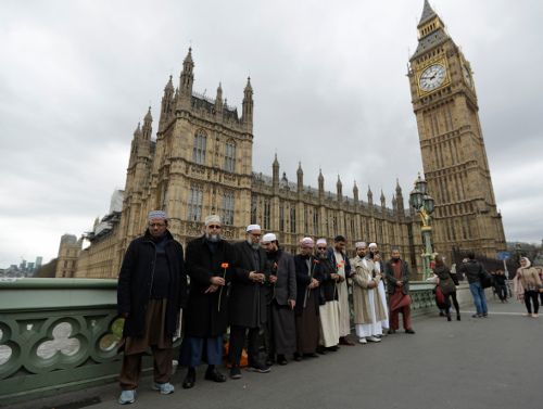 People arrive to take part in a vigil on Westminster Bridge in London, Wednesday, March 29, 2017. British police officers will be linking hands with members of a Muslim youth group on a London bridge to mark last week's attack outside Parliament that killed four people. (AP Photo/Matt Dunham)
