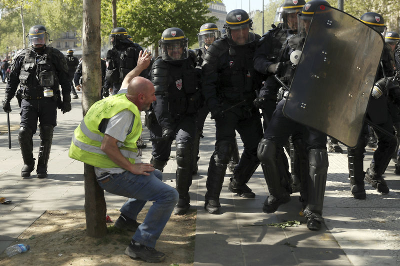 Police confront a protestor during a yellow vest demonstration in Paris, Saturday, April 20, 2019. French yellow vest protesters are marching anew to remind the government that rebuilding the fire-ravaged Notre Dame Cathedral isn't the only problem the nation needs to solve. (AP Photo/Francisco Seco)