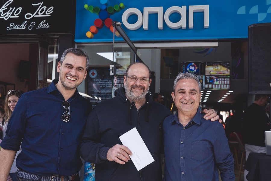 Ο Chief Retail Officer του ΟΠΑΠ, Ηλίας Κατσαρός,  με τον νικητή της κλήρωσης και τον ΟΠΑΠ Stores Director, Βαγγέλη Γκεβέζο