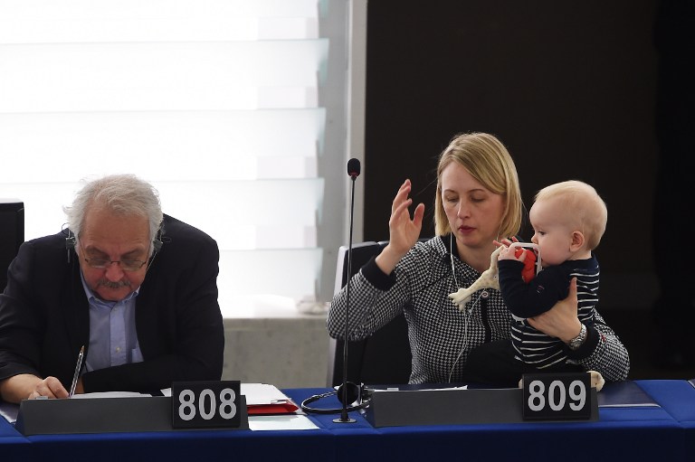Member of the European Parliament Swedish Jytte Guteland (R) holds her baby as she takes part in a voting session at the European Parliament in Strasbourg, eastern France, on March 14, 2017.  / AFP PHOTO / FREDERICK FLORIN