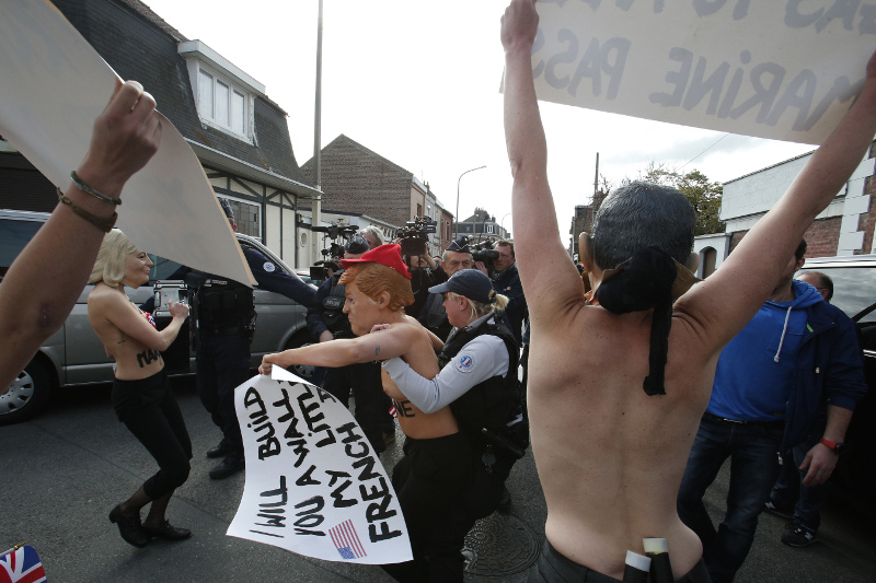 Femen activists, one wearing the mask of U.S president Donald Trump, are detained as they demonstrate  in Henin Beaumont, northern France, where far-right leader and presidential candidate Marine Le Pen will vote, during the first round of the French presidential election, Sunday April 23, 2017. (AP Photo/Michel Spingler)
