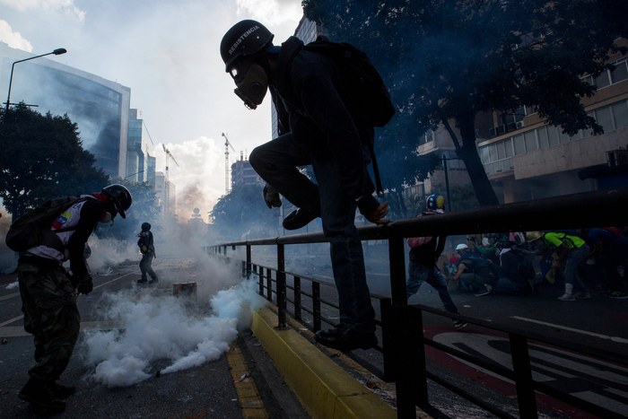 epa05977856 Protesters wearing gas masks clash with members of the Bolivarian National Guard (GNB) during an anti-government march in Caracas, Venezuela, 20 May 2017. Venezuelan security forces used tear gas to disperse demonstrators who were trying to reach the headquarters of the Interior Ministry, in the city center. Anti-government demonstrators have led protests against Venezuelan President Nicolas Maduro for 50 days paralyzing the divided country. At least 47 people died in violence related to the protests, media reported.  EPA/MIGUEL GUTIERREZ