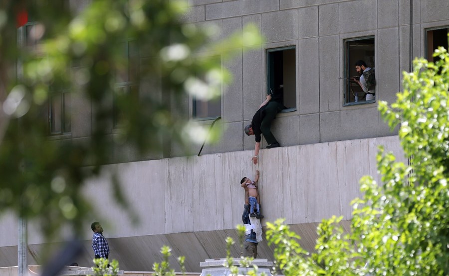 epa06014225 Iranian policemen try to help civilians fleeing from the parliament building during an attack in Tehran, Iran, 07 June 2017. At least seven people were killed and several others were wounded following twin attacks on Iran's parliament building and the mausoleum of former supreme leader, Ayatollah Khomeini, in the Iranian capital Tehran on 07 June, according to official sources.  EPA/OMID WAHABZADEH