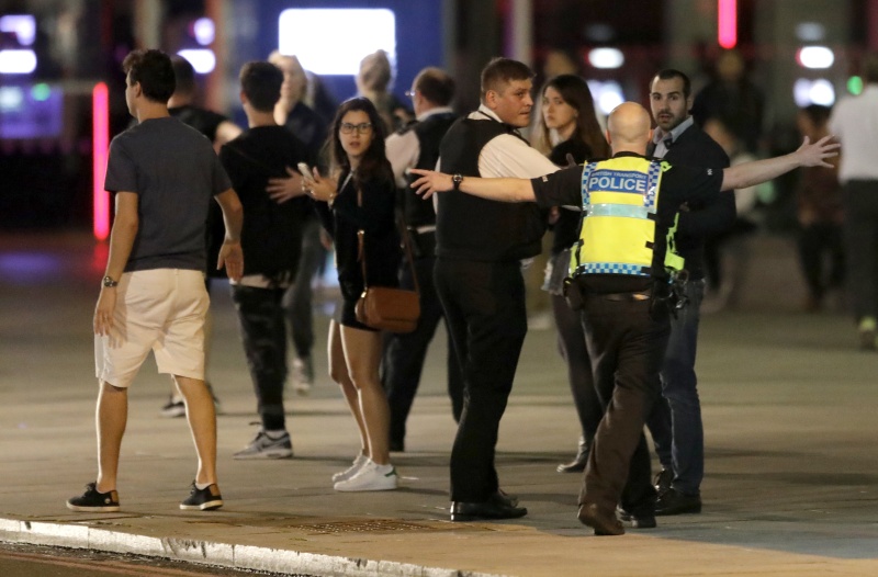 A Police officer clears people away from the area near London Bridge after an incident in central London, late Saturday, June 3, 2017.  British police said they were dealing with "incidents" on London Bridge and nearby Borough Market in the heart of the British capital Saturday, as witnesses reported a vehicle veering off the road and hitting several pedestrians. (AP Photo/ Matt Dunham)