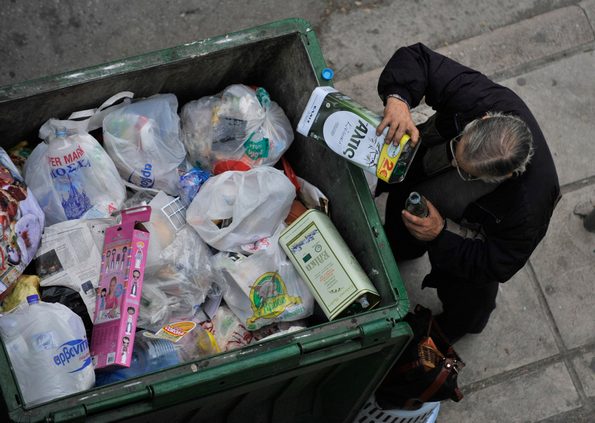 A man empties out the remains of an olive oil container from a trash bin in the northern Greek port city of Thessaloniki, Greece, Tuesday, Jan. 4, 2011. Welfare agencies and charity groups have warned of a spike in poverty and homelessness in Greece due to the effects of the financial crisis. (AP Photo/Nikolas Giakoumidis)