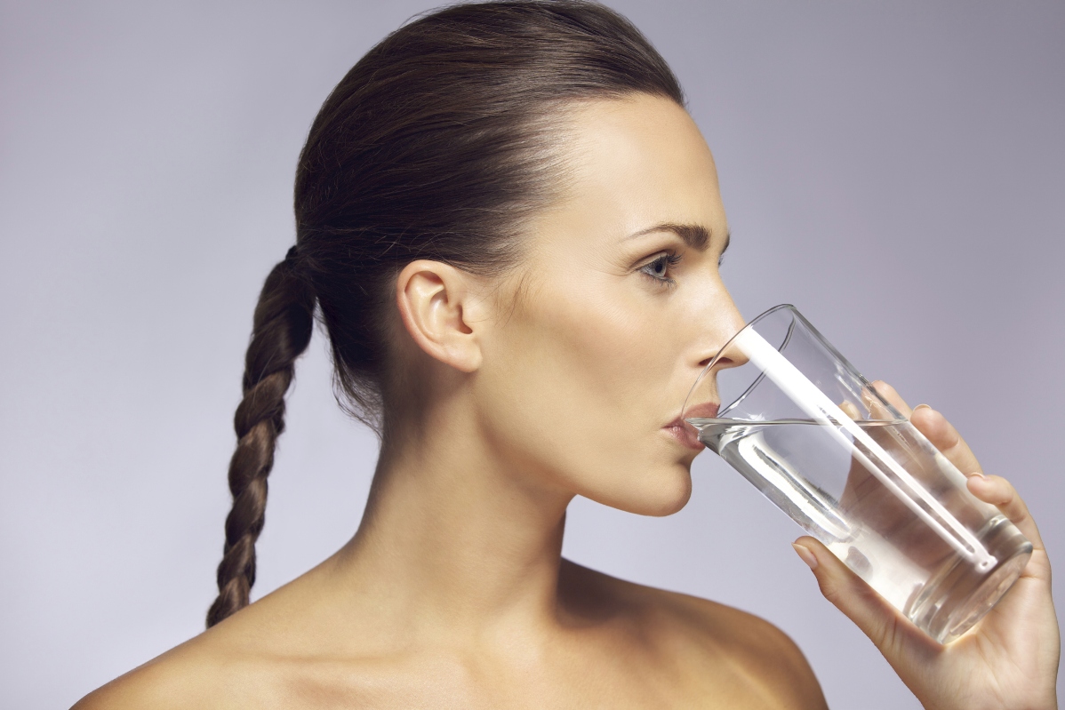Young beautiful woman drinking a glass of mineral water
