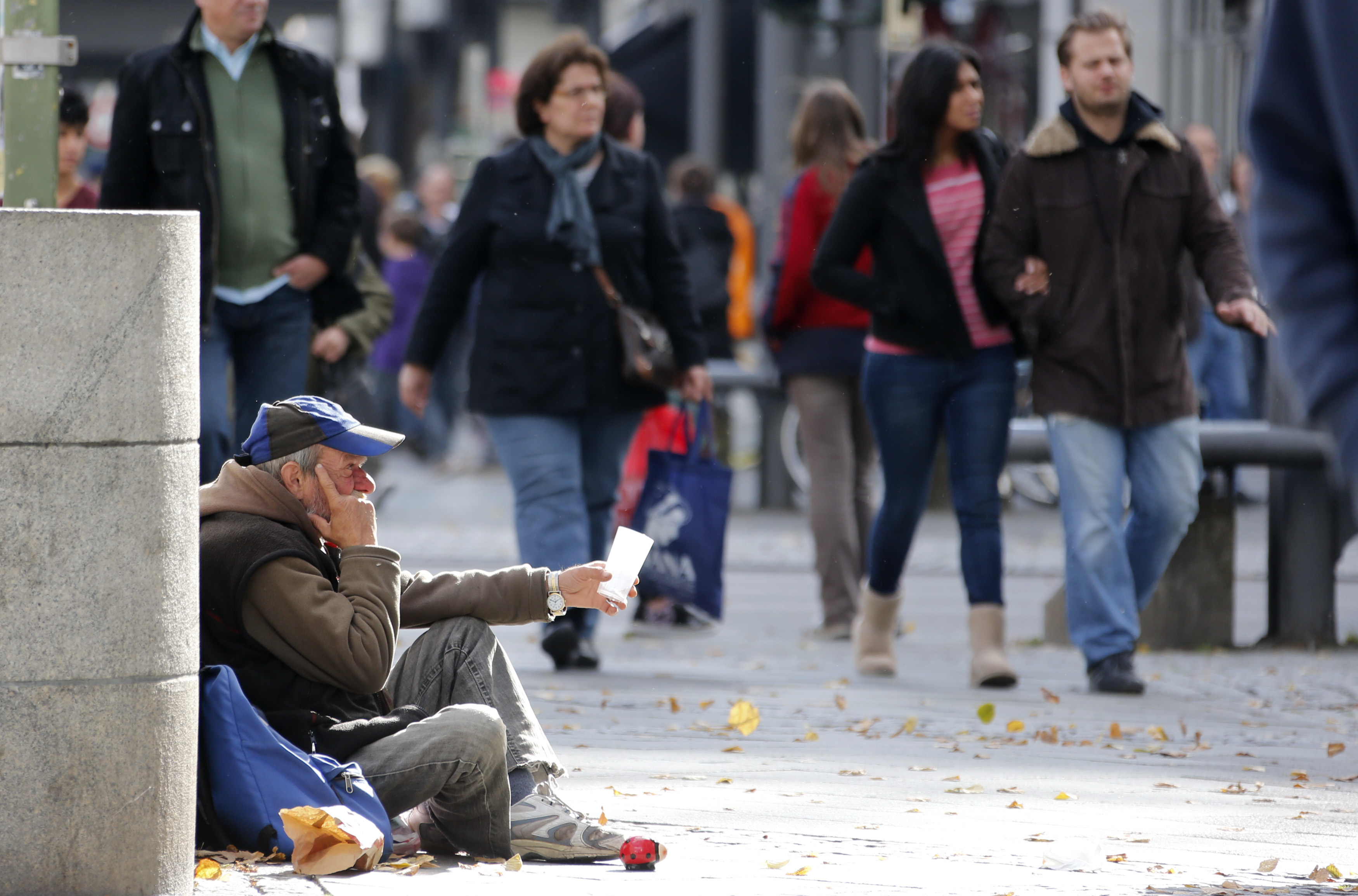 A man begs as pedestrians walk past at Wilmersdorfer shopping street in Berlin October 9, 2012.      REUTERS/Fabrizio Bensch (GERMANYSOCIETY BUSINESS - Tags: SOCIETY BUSINESS EMPLOYMENT) - RTR38YEX