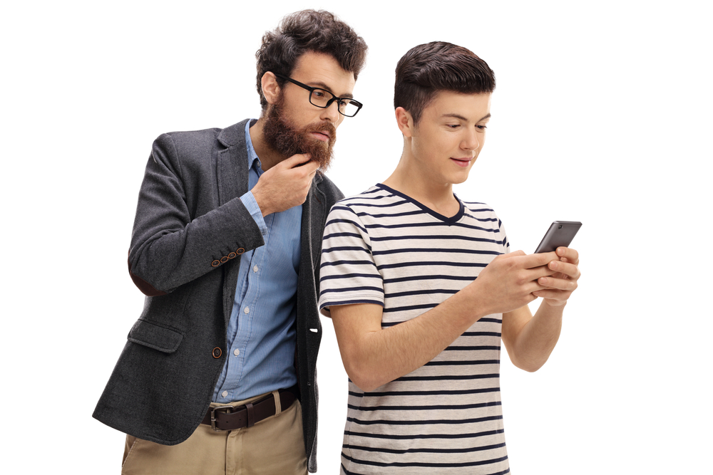Concerned father looking at the phone of his teenage son isolated on white background