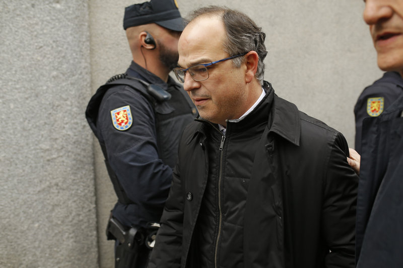 Catalan presidential candidate Jordi Turull walks past Spanish police officers as he arrives to the Supreme Court after a break for lunch in Madrid, Friday, March 23, 2018. Judge Pablo Llarena ordered five of the Catalan politicians who answered a court summons to be held without bail. Another of the summoned politicians, the ERC party's Marta Rovira, did not heed the order and announced in a letter she was fleeing the country to live in exile. (AP Photo/Francisco Seco)