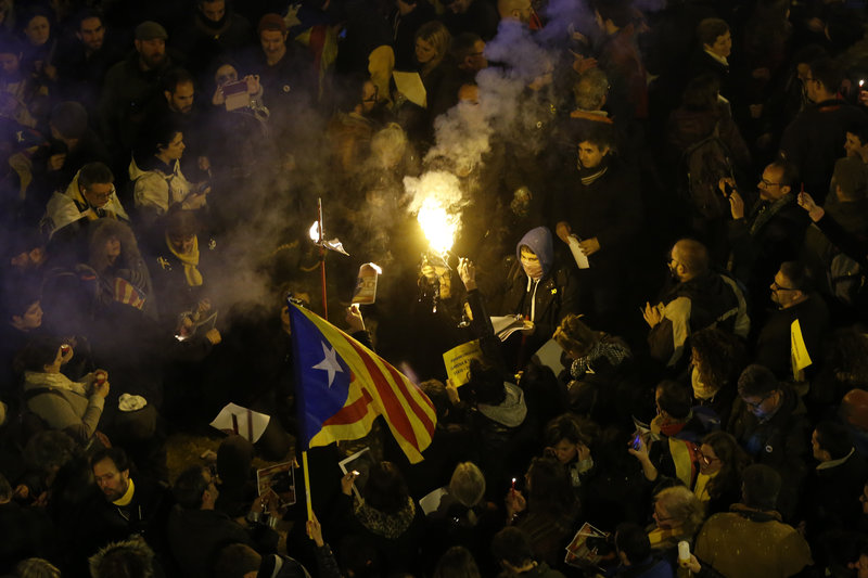People burn a photo of Spain's Prime Minister Mariano Rajoy during a protest over the jailing of Catalan politicians, Barcelona, Spain, Friday, March 23, 2018. A Spanish Supreme Court judge has charged 13 leading Catalan separatist politicians with rebellion for their recent attempts to bring about the region's independence from Spain. The indictment deals a heavy blow to the secessionist movement as it could put its political elite behind bars for decades. (AP Photo/Manu Fernandez)