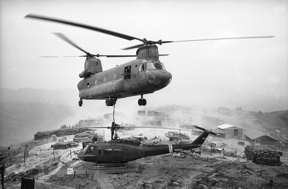 At a hilltop firebase west of Chu Lai in Vietnam, a huge army "Chinook" helicopter prepares to lift a conked-out smaller one to a base for repairs, April 27, 1969. The firebase was named LZ West and was manned by the troopers of the 196th Light Infantry Brigade forming part of the American Division. The smaller helicopter - a Huey UH-ID - had developed engine trouble so its crew chief called in the local aerial towing service. One sturdy nylon strap to the chopper's winch and the two were off. (AP Photo/Oliver Noonan)