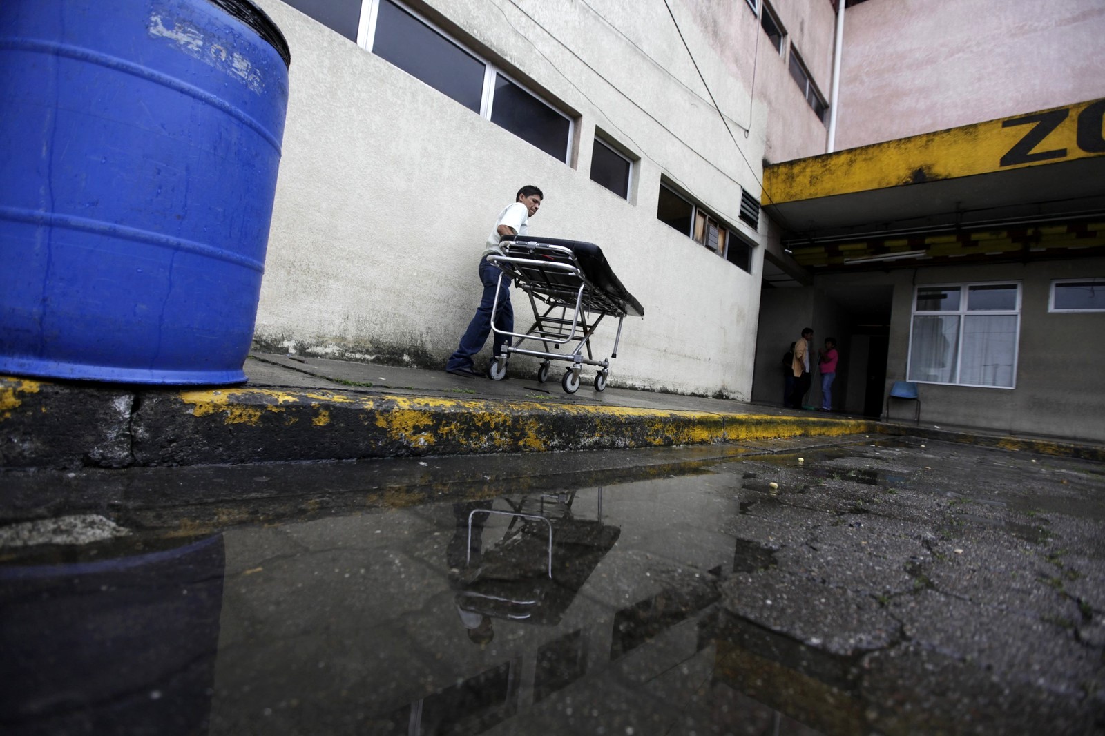 A man pushes a stretcher after taking a body to the morgue of a local hospital in San Pedro Sula March 27, 2013. San Pedro Sula, the country's second largest city after Tegucigalpa, has a homicide rate of 169 per 100,000 people and was named the world's most violent city for a second year in a row. Lax laws allow civilians to own up to five personal guns. Arms trafficking has flooded the country with nearly 70% illegal firearms. 83.4% of homicides are by firearms, compared to 60% in the United States. Picture taken March 27, 2013. REUTERS/Jorge Cabrera (HONDURAS - Tags: CRIME LAW CIVIL UNREST HEALTH) ATTENTION EDITORS: PICTURE 14 OF 39 FOR PACKAGE 'GUN CULTURE - HONDURAS' SEARCH 'HONDURAS GUN' FOR ALL IMAGES