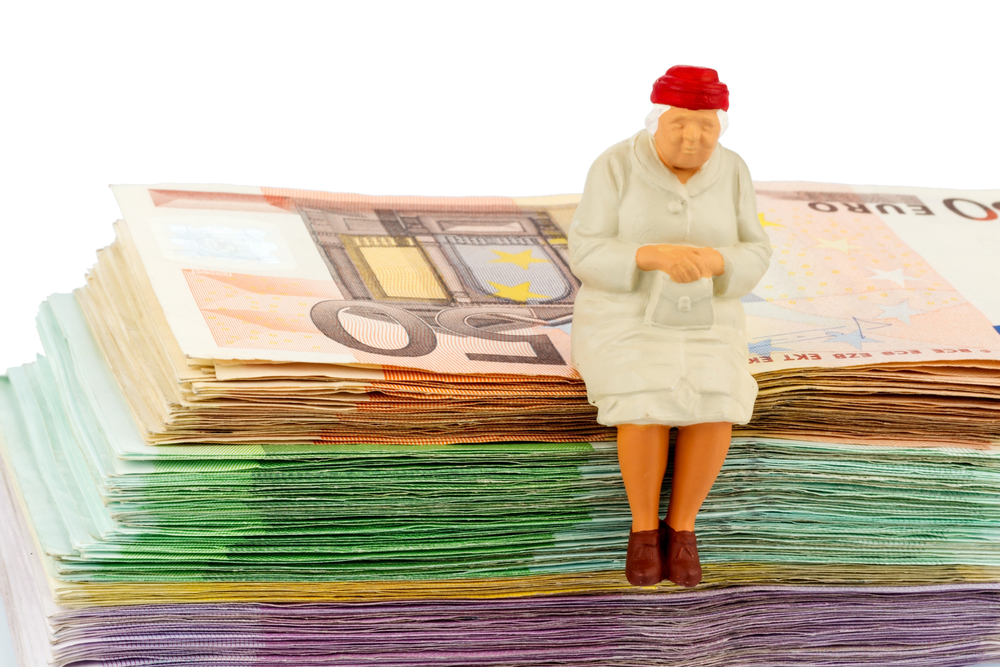 figure of an old woman sitting on a stack of bills, symbolic photo for pension and retirement