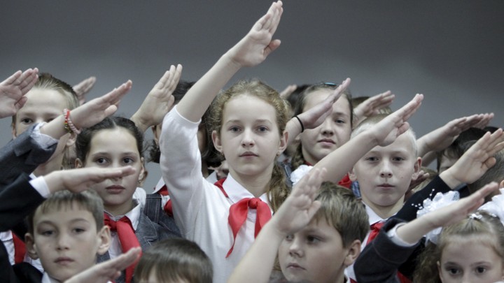 Children, wearing red neckerchiefs, a symbol of the Pioneer Organization, salute while posing for a picture during a ceremony for the inauguration of 18 newly adopted members at a local school in the southern settlement of Kazminskoye in Stavropol region, Russia, November 19, 2015. Early pro-communist youth movements, which appeared in Russia after the 1917 Bolshevik revolution, were reformed into the Pioneer Organization of the Soviet Union. While the organization lost its dominance among students in post-Soviet Russia, some educational institutions and families still carry on this tradition. REUTERS/Eduard Korniyenko - RTS7YMY