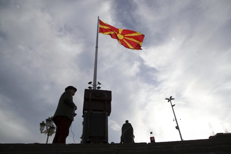 A street artist prepares his performance as the Macedonian flag flies over the main square of Skopje, Friday, Sept. 28, 2018. A referendum set for Sunday in Macedonia seeks voter support for changing the Balkan nation's name to North Macedonia. Greece has agreed to drop longstanding objections to neighboring Macedonia joining NATO and eventually becoming a member of the European Union, if the new name is approved. (AP Photo/Thanassis Stavrakis)