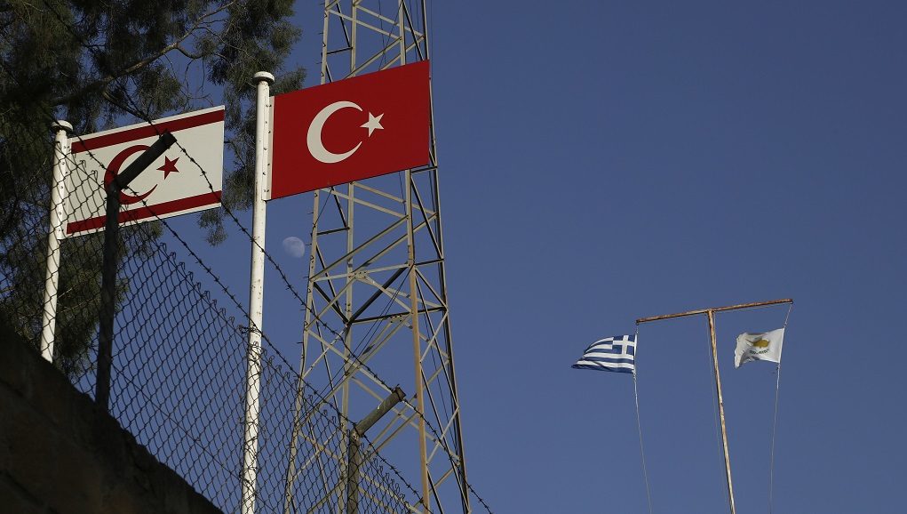 Turkish, right, and Turkish Cypriots breakaway flags are seen on the left as a Greek, left, and Cyprus' flags are seen on the right, on the abandoned military guard post at Pafos gate at the venetian wall that surrounds the old city of divided capital Nicosia, Cyprus, on Tuesday, July 4, 2017. At talks to end Cyprus' 43-year ethnic divide at the Swiss ski resort of Crans-Montana, Turkish Foreign Minister Mevlut Cavusoglu, made it clear that a peace accord would not include a specific, agreed-upon date by which all Turkish troops would have to be pulled out. (AP Photo/Petros Karadjias)
