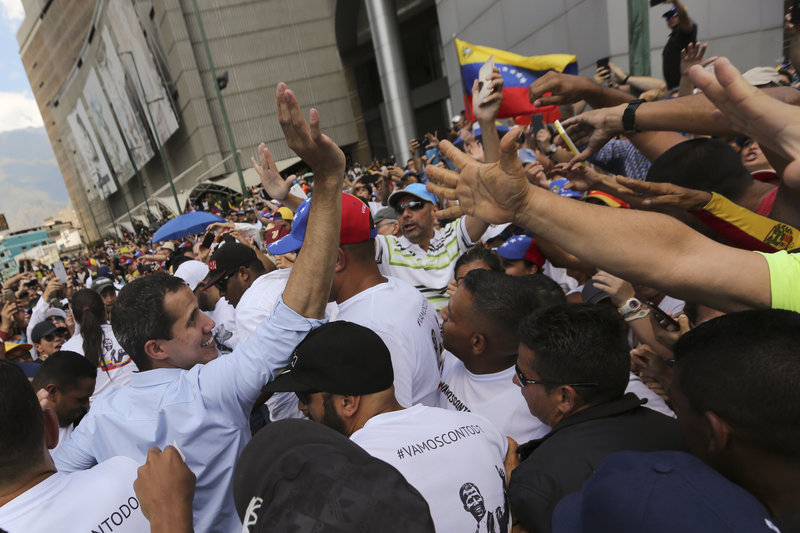 Opposition leader and self-proclaimed interim president Juan Guaido, left, is surrounded by supporters after speaking in a rally to protest outages that left most of the country scrambling for days in the dark in Caracas, Venezuela, Saturday, April 6, 2019. (AP Photo/Fernando Llano)