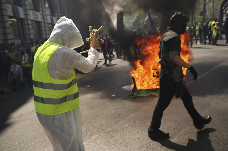 Two protestors walk by a pile of wood burning in the street during a yellow vest demonstration in Paris, Saturday, April 20, 2019. French yellow vest protesters are marching anew to remind the government that rebuilding the fire-ravaged Notre Dame Cathedral isn't the only problem the nation needs to solve. (AP Photo/Francisco Seco)