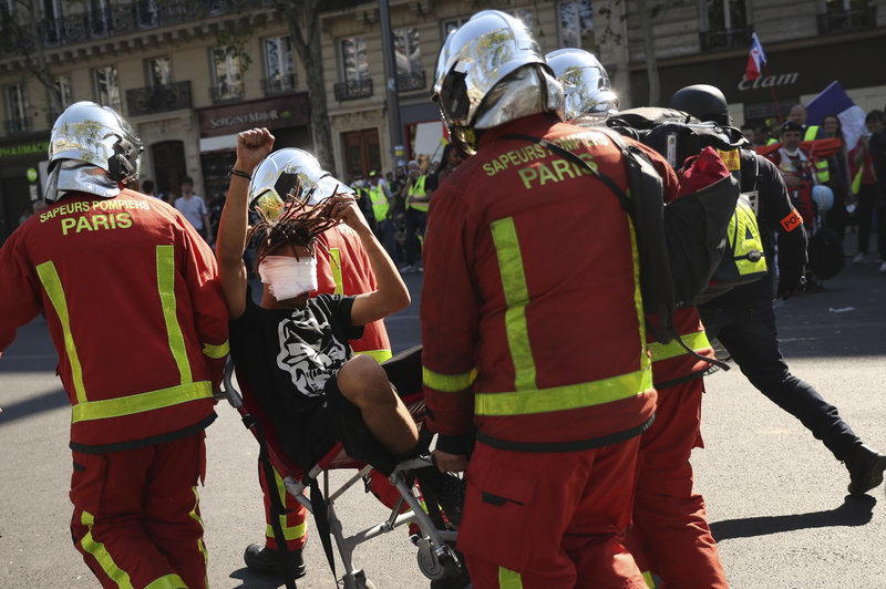 An injured man is carried away by emergency personnel during a yellow vest demonstration in Paris, Saturday, April 20, 2019. French yellow vest protesters are marching anew to remind the government that rebuilding the fire-ravaged Notre Dame Cathedral isn't the only problem the nation needs to solve. (AP Photo/Francisco Seco)