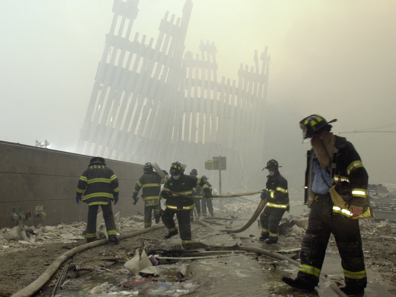 Firefighters work beneath the destroyed mullions, the vertical struts which once faced the soaring outer walls of the World Trade Center towers, after a terrorist attack on the twin towers of lower  Manhattan Tuesday, Sept. 11, 2001. As workers cleared some of the rubble, new crews of firefighters and rescue workers charged into the devastation with shovels, pickaxes and flashlights to look for bodies or survivors. (AP Photo/Mark Lennihan)