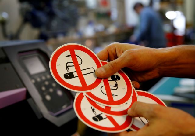 FILE PHOTO: An employee shows no-smoking signs in the a printing shop in Vienna, Austria March 8, 2018.   REUTERS/Leonhard Foeger/File Photo