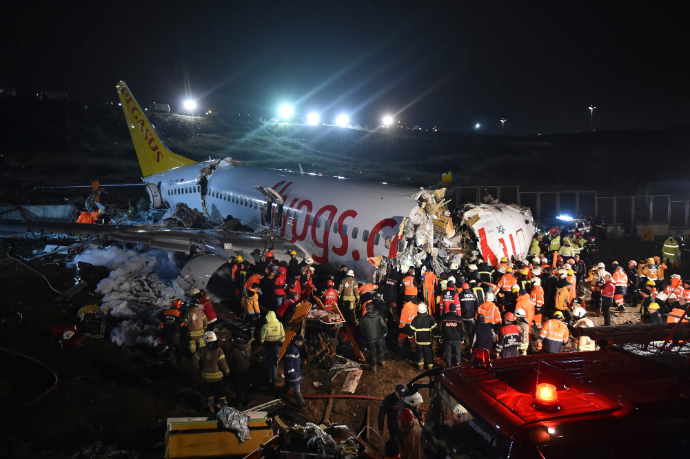 Rescue members and firefighters work around the wreckage of a plane after it skidded off the runway at Istanbul's Sabiha Gokcen Airport, in Istanbul, Wednesday, Feb. 5, 2020. A plane skidded off the runway Wednesday at Istanbul’s Sabiha Gokcen Airport, crashing into a field and breaking into pieces. Passengers were seen evacuating through cracks in the plane and authorities said dozens have been injured. (Ismail Coskun/IHA via AP)