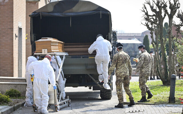A convoy of Italian Army trucks is unloaded upon arrival from Bergamo carrying bodies of coronavirus victims to the cemetery of Ferrara, Italy, where they will be cremated, Saturday, March 21, 2020. The transfer was made necessary since Bergamo mortuary reached maximum capacity. For most people, the new coronavirus causes only mild or moderate symptoms. For some it can cause more severe illness, especially in older adults and people with existing health problems. (Massimo Paolone/LaPresse via AP)