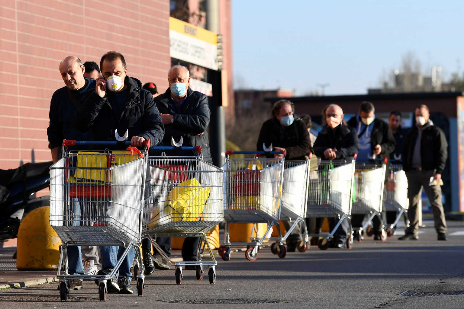 People wearing protective face masks arrive a supermarket on the second day of an unprecedented lockdown across all of the country, imposed to slow the outbreak of coronavirus, in Pioltello, near Milan, Italy March 11, 2020. REUTERS/Flavio Lo Scalzo