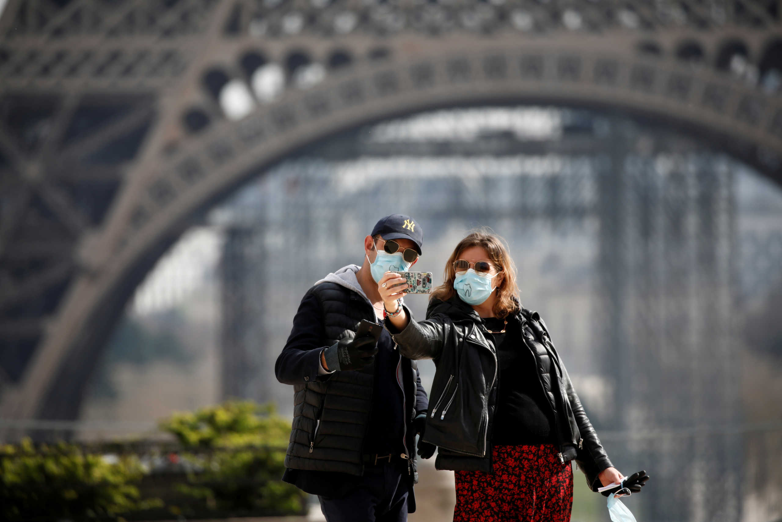 FILE PHOTO: A couple wearing protective masks take a selfie in front of the Eiffel Tower as lockdown is imposed to slow the spreading of the coronavirus disease (COVID-19) in Paris, France, March 18, 2020. REUTERS/Benoit Tessier/File Photo