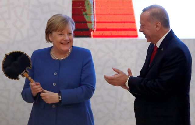 German Chancellor Angela Merkel holds a gift next to Turkish President Tayyip Erdogan during the official opening ceremony of Turkish-German University's new campus in Istanbul, Turkey, January 24, 2020. REUTERS/Umit Bektas