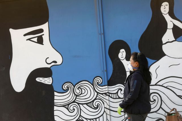 A woman wears a protective mask near to a mural in the Sicilian city of Messina, after Sicily requested that transport to the island would be blocked from mainland Italy as part of measures to contain coronavirus contagion on the island, in Messina, Italy March 16, 2020. REUTERS/Antonio Parrinello