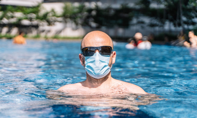 portrait of a tourist couple wearing a protective mask inside the pool for fear of the coronavirus covid19