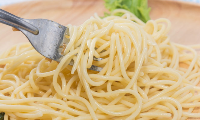 spaghetti without sauce with fork on wooden plate