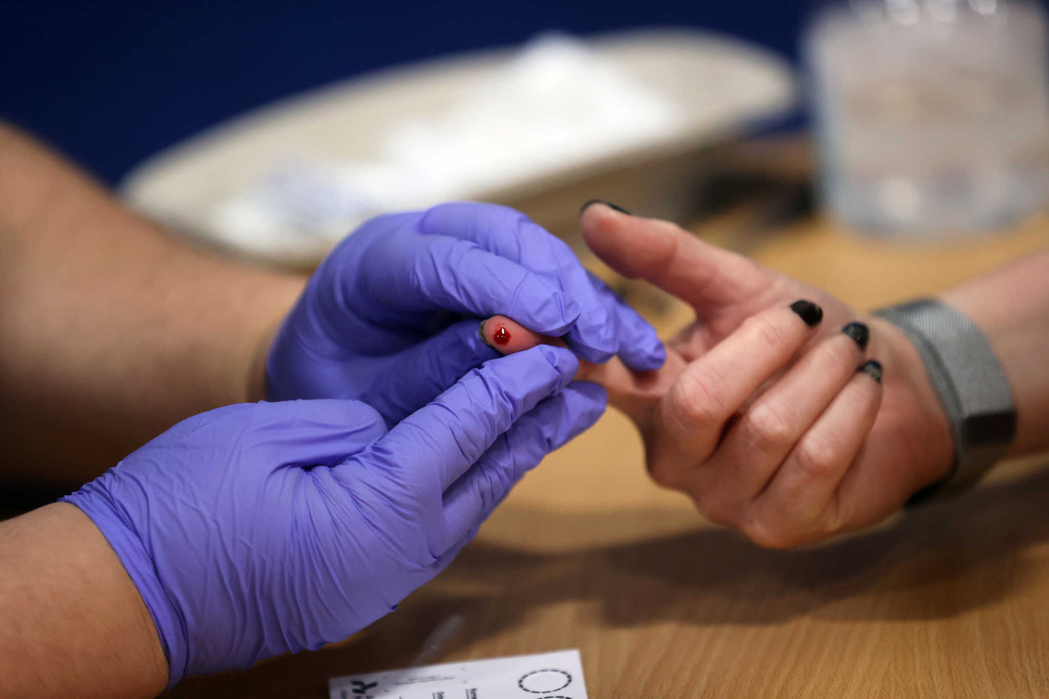 A worker takes a blood sample from a woman during a clinical trial of tests for the coronavirus disease (COVID-19) antibodies, at Keele University, in Keele, Britain June 30, 2020. REUTERS/Carl Recine