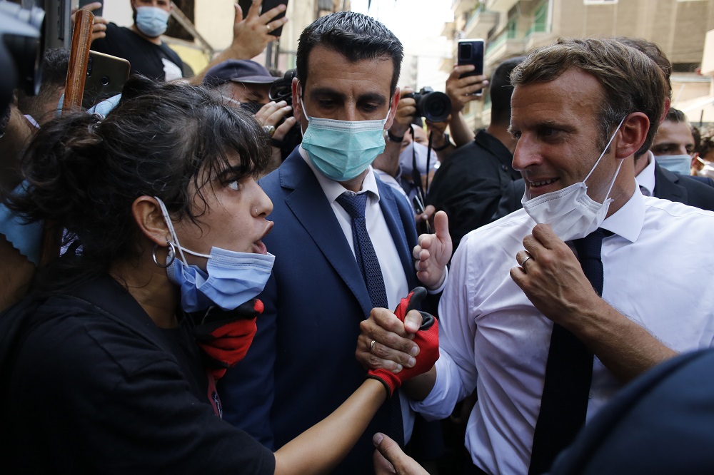 French President Emmanuel Macron listens to a resident as he visits a devastated street of Beirut, Lebanon, Thursday Aug.6, 2020. French President Emmanuel Macron has arrived in Beirut to offer French support to Lebanon after the deadly port blast.(AP Photo/Thibault Camus, Pool)