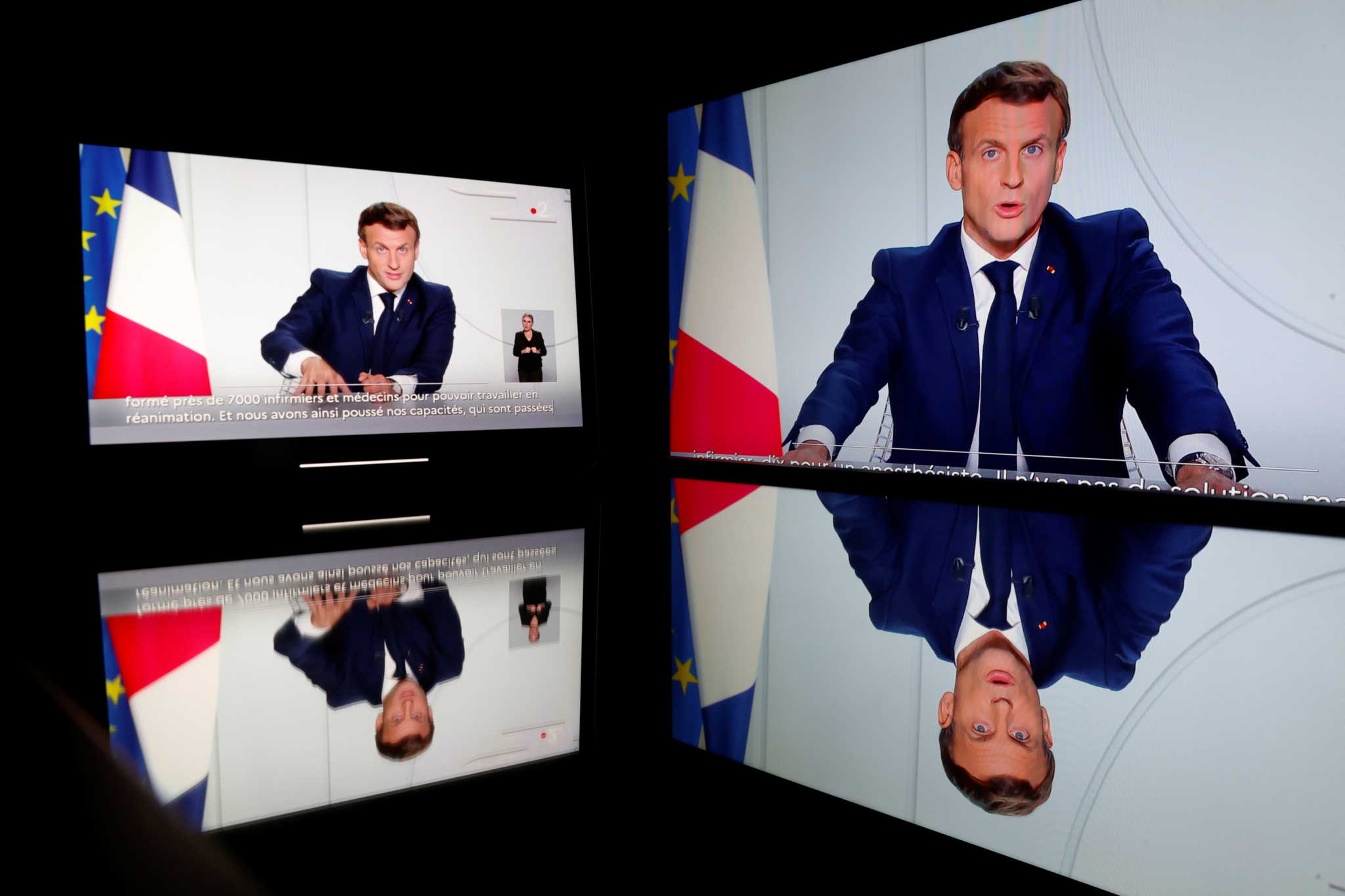 French President Emmanuel Macron is seen on screens as he addresses the nation about the state of the coronavirus disease (COVID-19) outbreak in France in this illustration picture, October 28, 2020. REUTERS/Christian Hartmann/Illustration