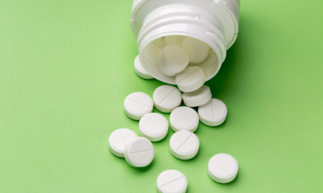 Heap of round white tablets and plastic pills bottle