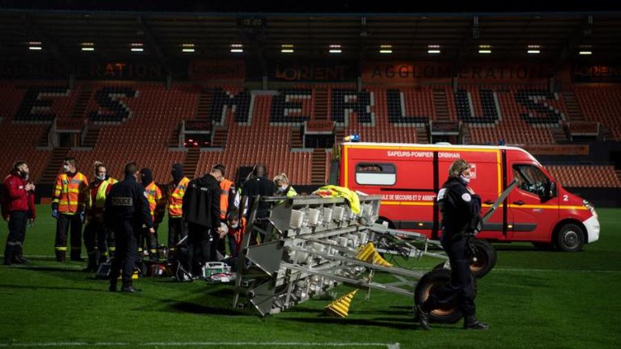 Members of the medical staff and firemen try to rescue a man in critical conditions, who's lying on the football picth after he was hit by the fall of a heater (R) at the end of the French L1 football match between FC Lorient and Stade Rennais at the Moustoir Stadium in Lorient, western France, on December 20, 2020. (Photo by LOIC VENANCE / AFP)