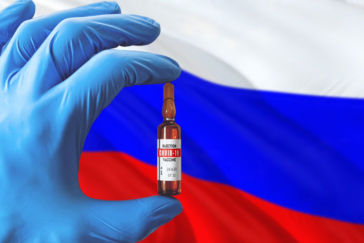 Russia flag with Coronavirus Covid-19 concept. Doctor with blue protection medical gloves holding a vaccine bottle. Epidemic Virus, Cov-19, Corona virus outbreaking.
